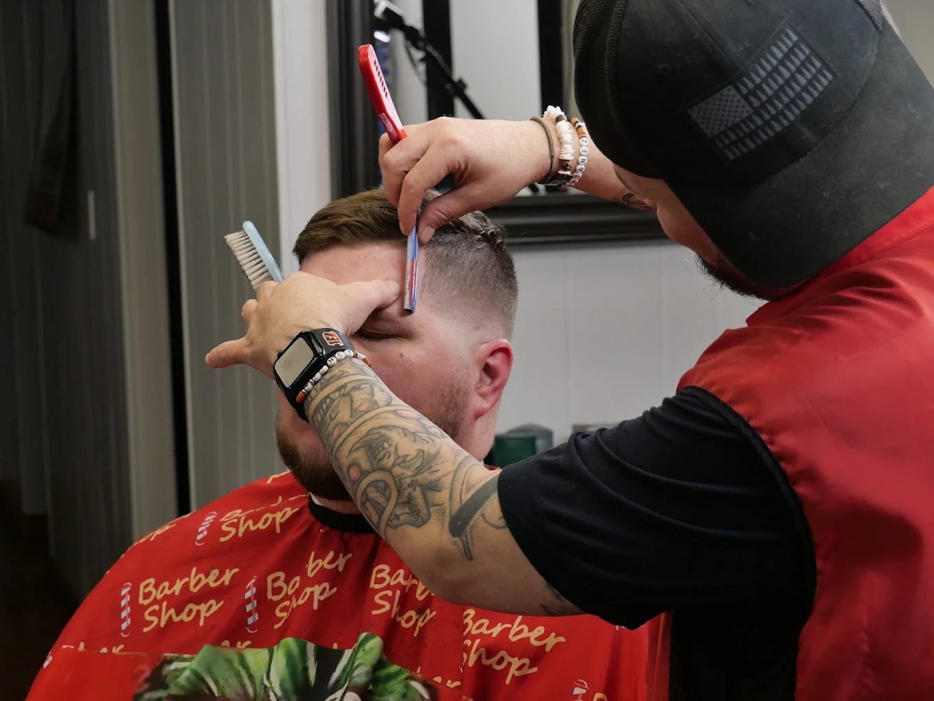Barber lining up a client's hairline with a straight razor
